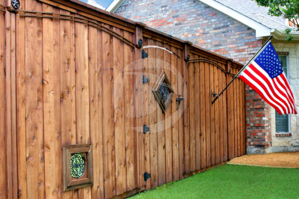 Stained board on board cedar fence with black ornamental hardware and gate fittings.