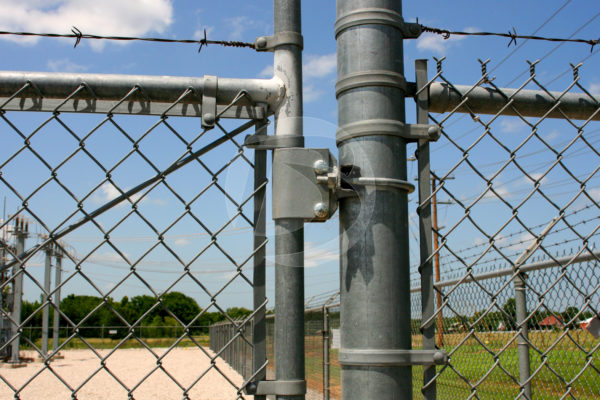 Galvanized gate hardware with barbed wire surrounding a power station