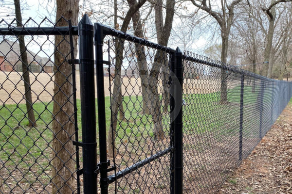 Black vinyl coated chain link around large backyard backing up to a wooded area