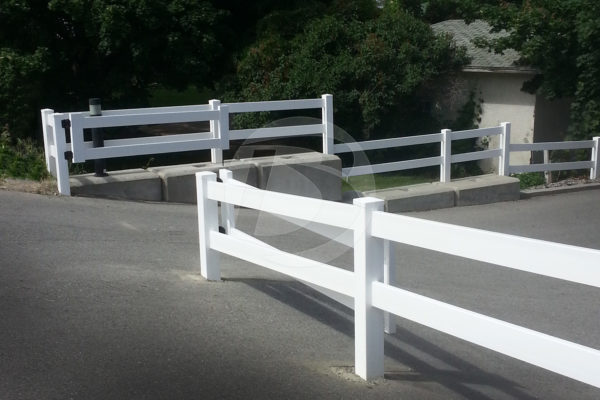 White 2-rail vinyl fence with a gate swing for parking lot