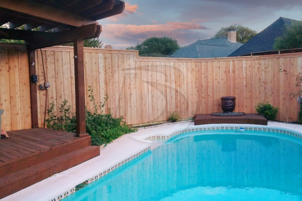 Board on Board unstained cedar fence with a stained cedar arbor and deck around a pool