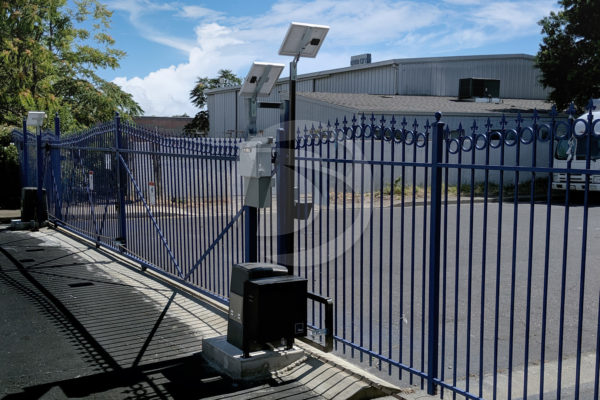 Custom made Blue arched 2-rail ornamental iron fence and matching roll gate with rings and fleur-de-lis with gate operator